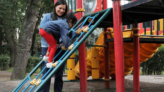 Mother playing with daughter on the playground.